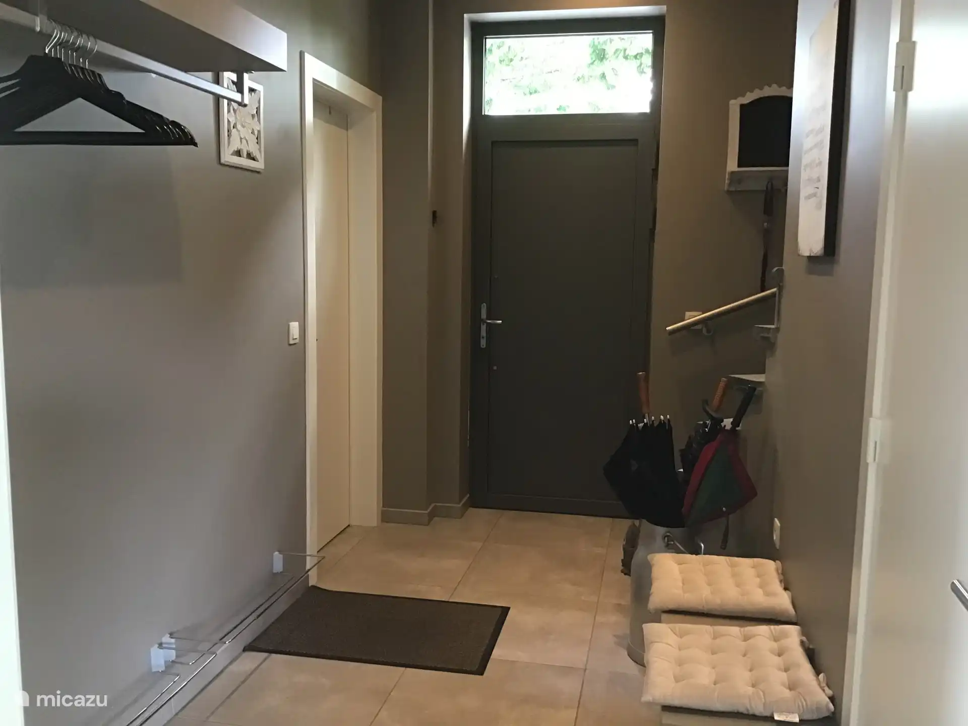 Inkomhal met zitbankje, schoenrekken en hangbaar voor jassen. Links deur slaapkamer. Rechts deur gastentoilet.
