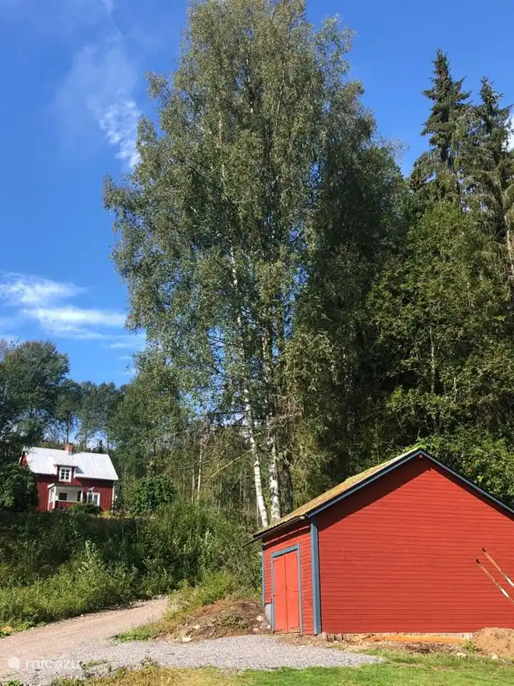 Die Garage mit einem Parkplatz daneben und Blick auf die schwedischen Nachbarn oben