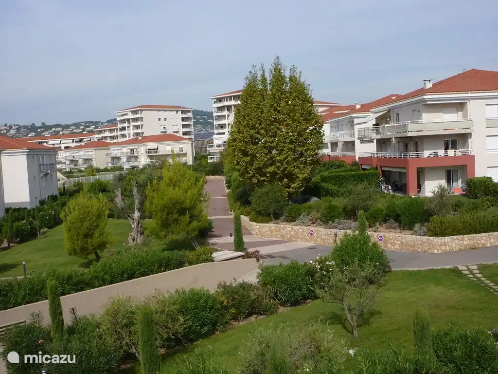 Overzicht van het pad naar het zwembad. Rechts op de eerste verdieping ziet u het grote balkon met de luxe tuinmeubels.