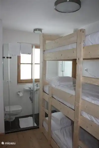 2nd bedroom with 3-layer bunk bed. Behind it the compact 2nd bathroom with glass wall.