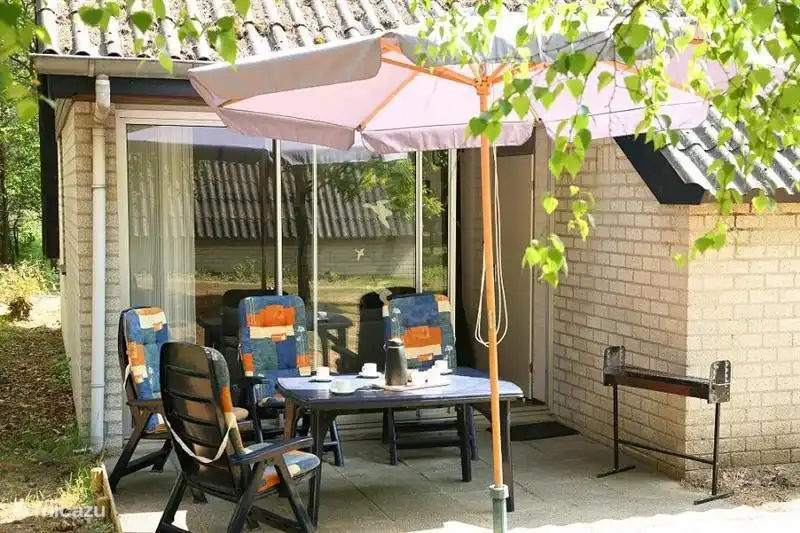 Terrasse mit Gartenmöbeln, Sonnenschirm, Grill.