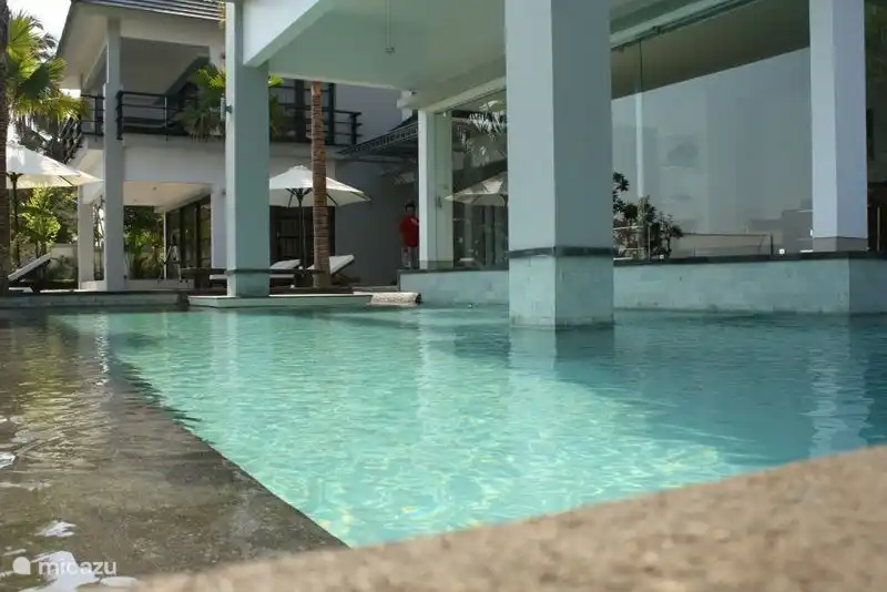 Der Pool von der Seite. Es hat eine L-Form und setzt sich an der Seite fort.