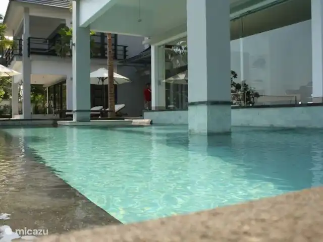Bali Villa Dunia Seni huren in Indonesië, Bali, Bukti - villa Het zwembad vanaf de zijkant. Het heeft een L vorm en loopt aan de zijkant door.