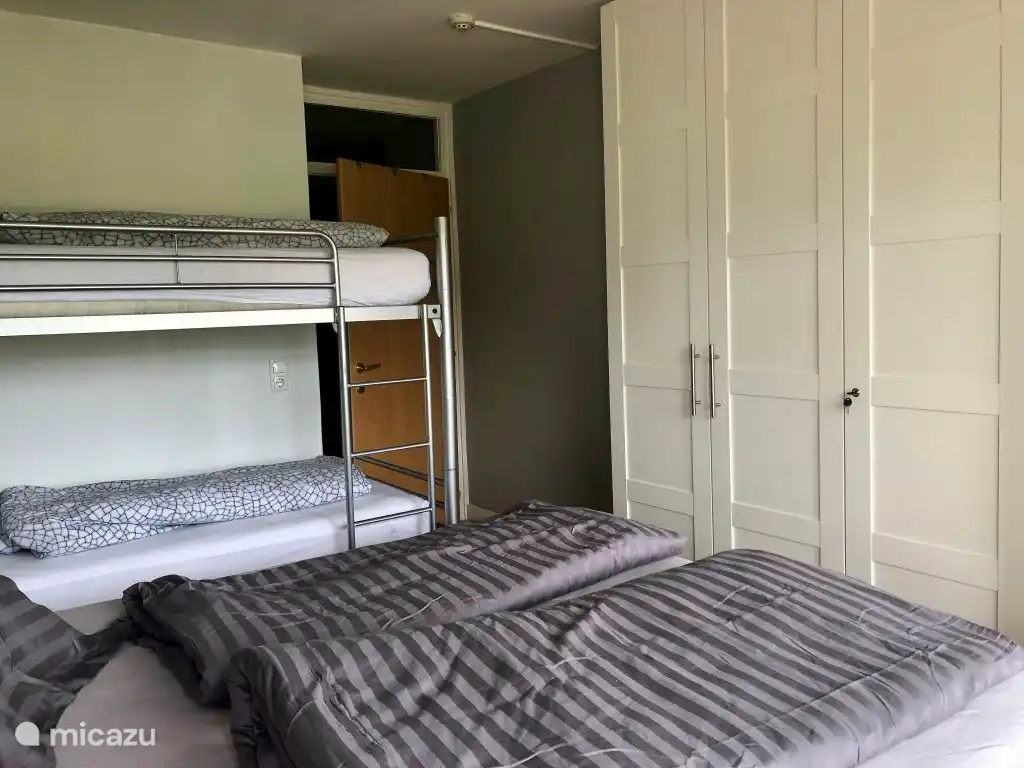 Spacious bedroom with double bed, bunk bed and linen cupboard.