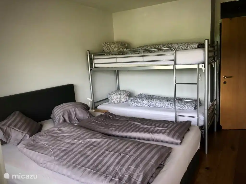 Spacious bedroom with double bed, bunk bed and linen cupboard.
