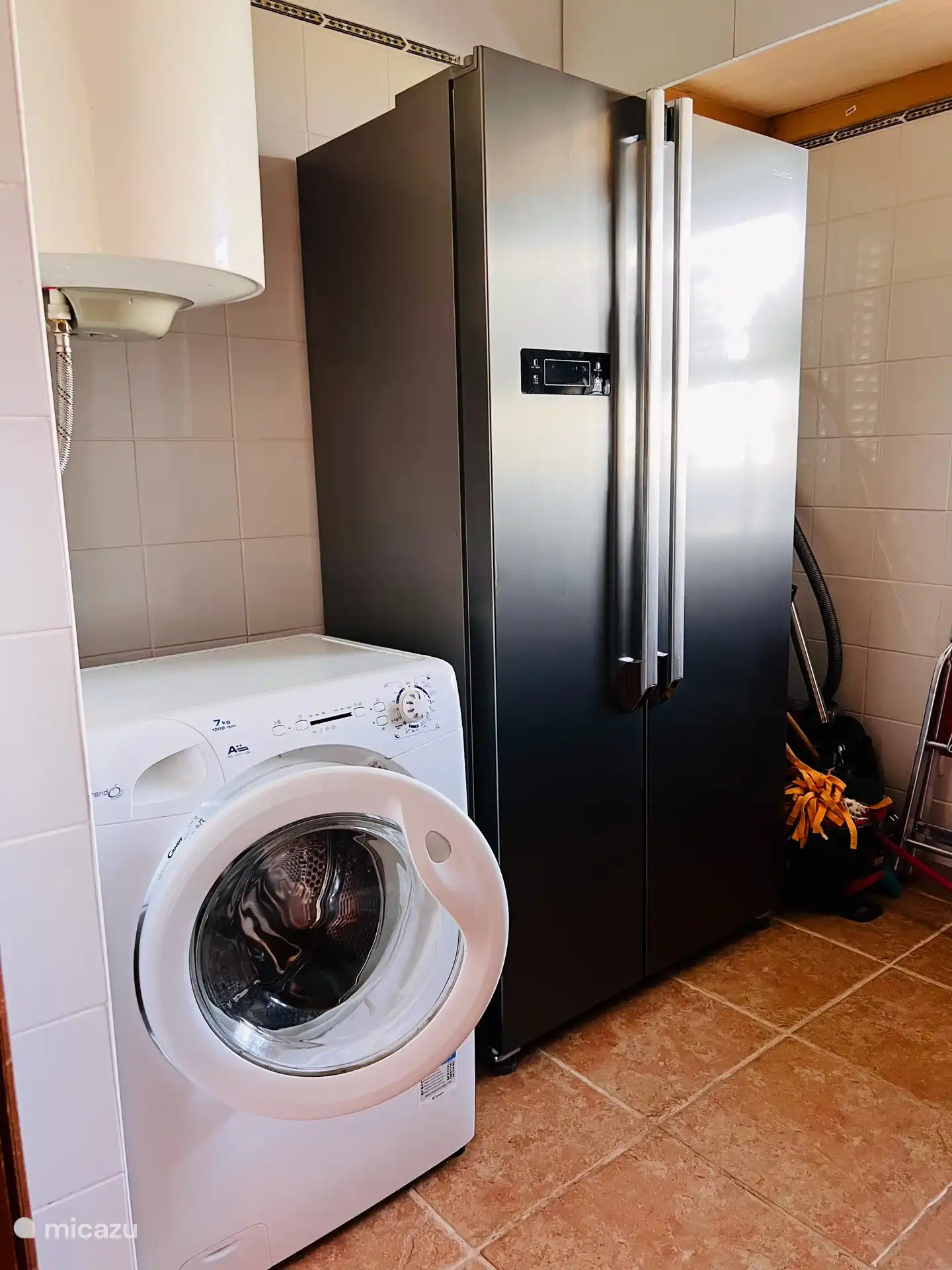 This utility room is very useful, there is a washing machine where you can keep track of your laundry. . And an American refrigerator. Very spacious. And on the left side is a freezer. Easy for larger groups. You can also find a cool box and some bags there. Also an ironing board and bolt, and storage space. 