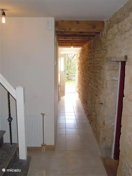 Les vieilles pierres sont visibles dans le hall ; à côté de l'escalier, il y a un espace meublé comme une armoire.