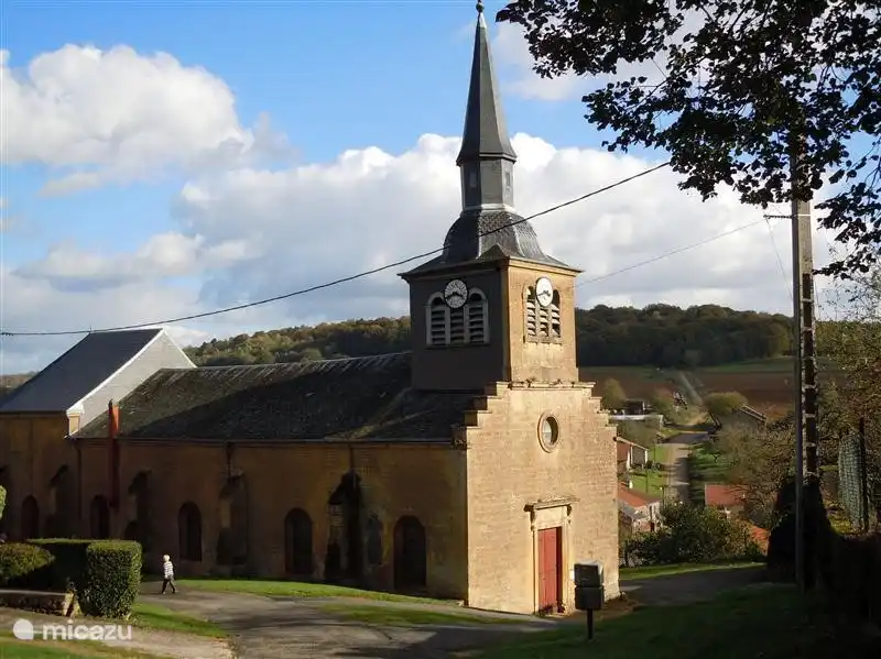 Vue sur l'église, le village, les champs et les collines.