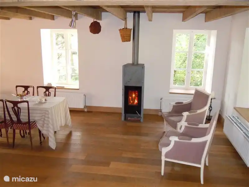Salle à manger avec une partie de la table à manger, qui est une extension de la cuisine. Il y a aussi deux jolis fauteuils dans cette partie pour s'asseoir au chaud près du poêle à bois.