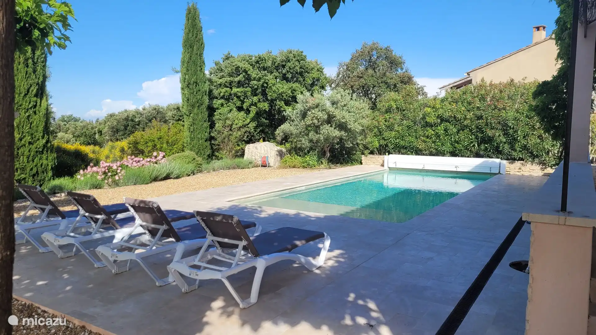 Zijaangezicht garden with private pool and sun loungers.