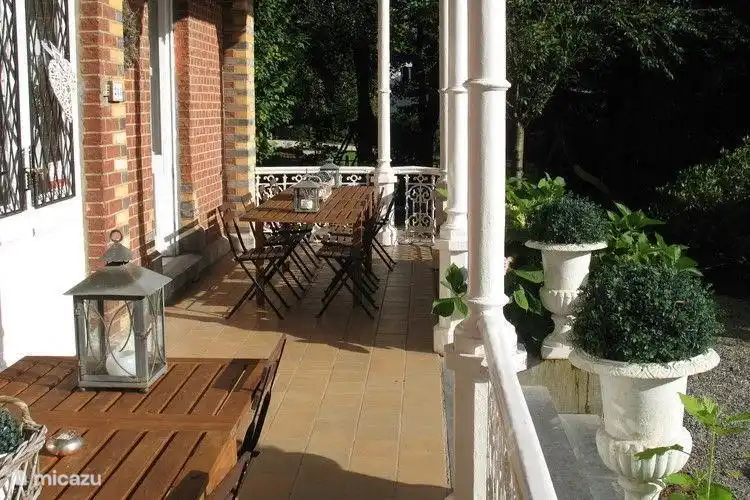 Veranda mit zwei langen Holztische mit 8 Stühlen.