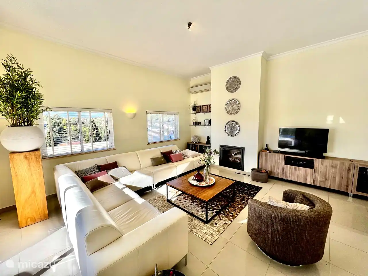 Salon avec cheminée, TV et climatisation.