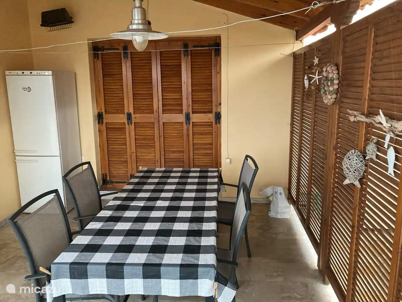 Überdachte Terrasse mit Außenkühlschrank und Meerblick zwischen Ferienhaus und Swimmingpool.