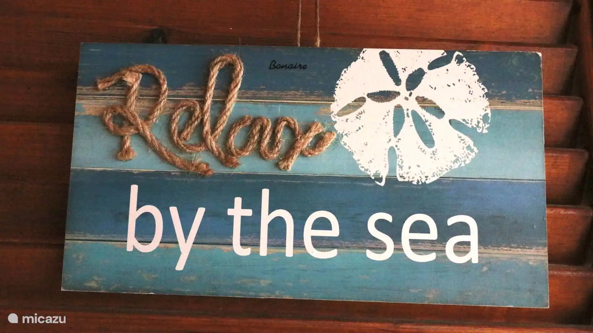 Holzschild auf Terrasse unter Unterstand