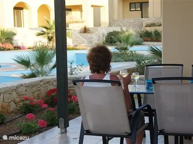 Villa Aphrodite en Grecia, Creta, Panormo - casa vacacional Hay vistas al mar desde la terraza privada. Las piscinas están dos escalones más abajo, el acceso está cerrado con una puerta baja. Hay una amplia mesa de comedor con cuatro sillas. Tumbonas y sillas también están disponibles en las piscinas.