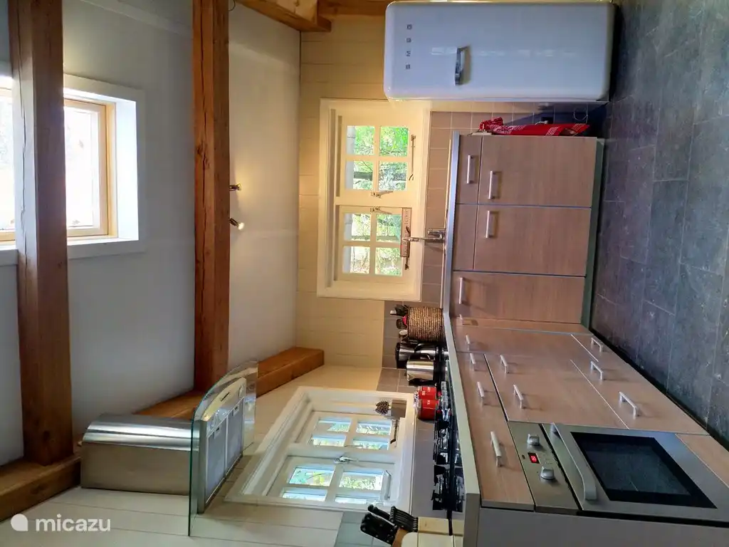 De open keuken met oven, vaatwasser en Smeg koelkast.