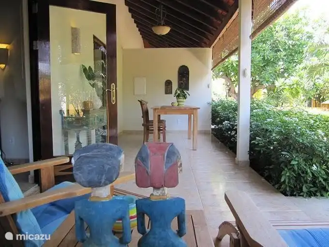 Het terras met makkelijke stoelen, eettafel en een uitzicht over de tropische tuin en zwembad.