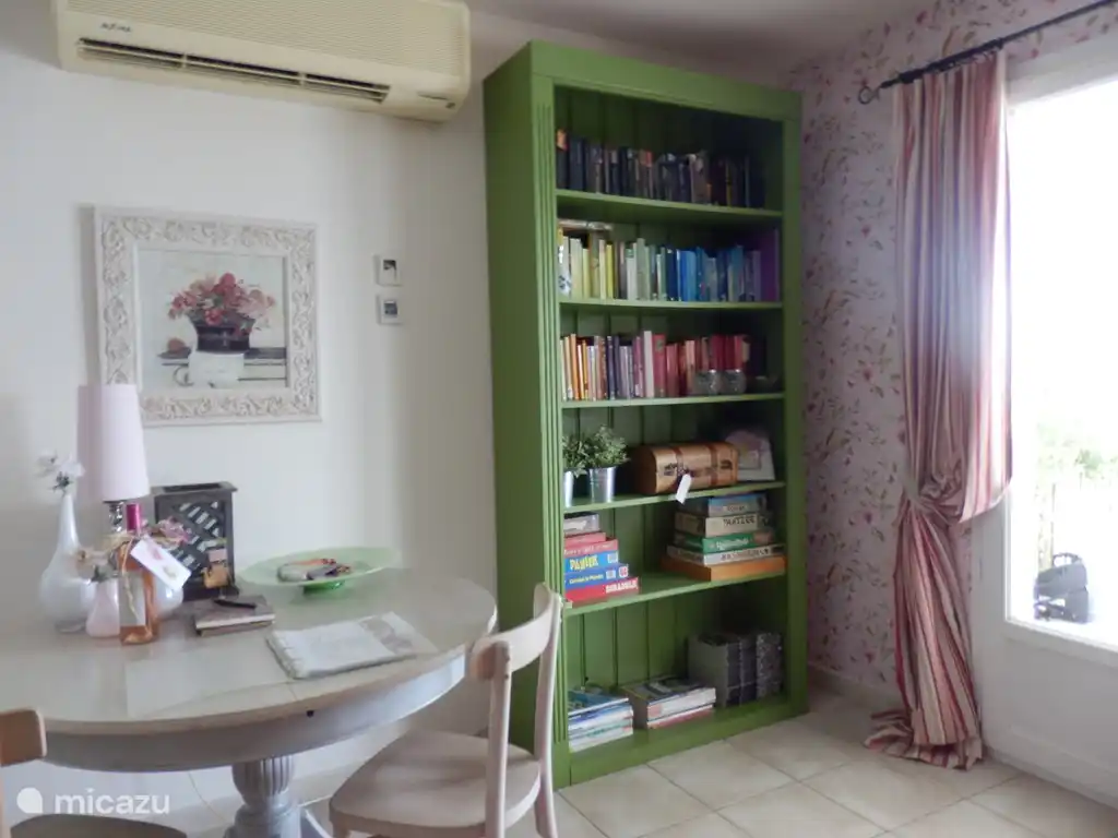 The cupboard with books and magazines in the other corner of the living room, with 1 of the 2 double doors opening onto the covered terrace.