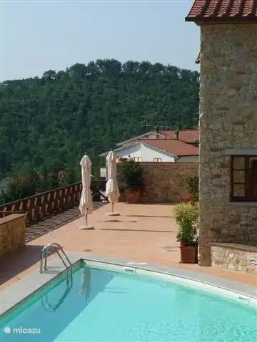 Junto a la piscina hay una amplia terraza con tumbonas y sombrillas 