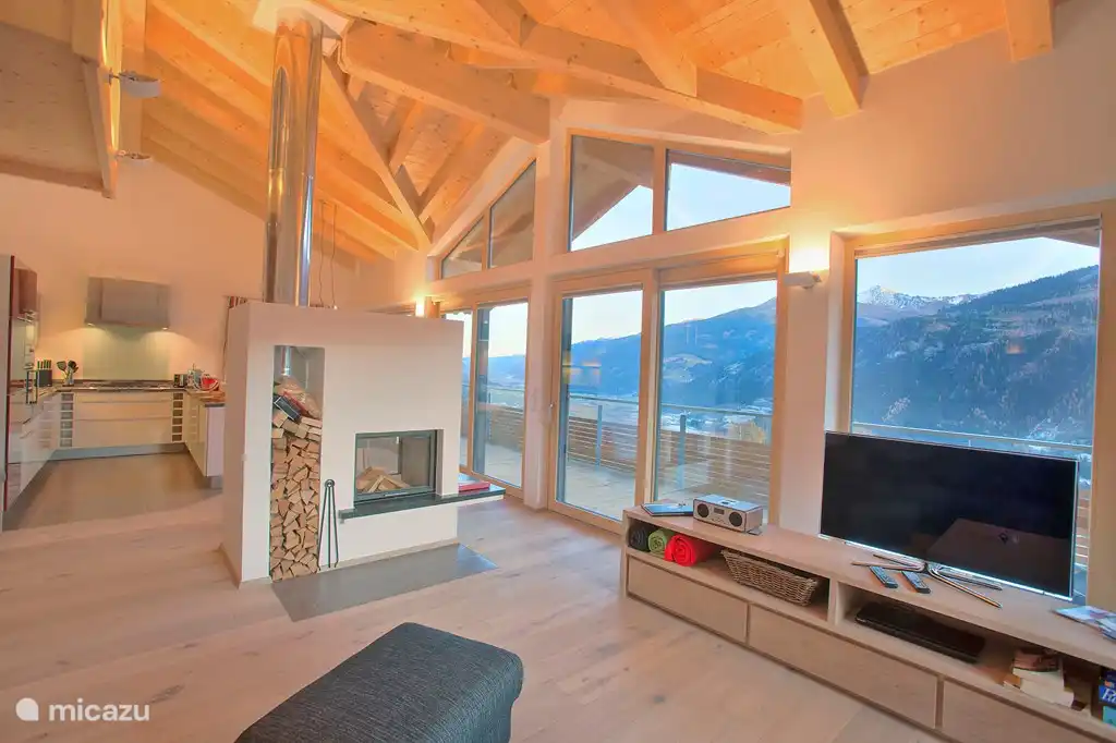 Séjour spacieux avec façade haute, cheminée, coin repas et coin salon. Belle vue sur la construction du toit.