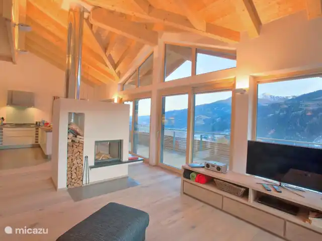 Location de Vacances Autriche, Salzburgerland, Bramberg am Wildkogel, chalet - Alpenchalet am Wildkogel - Émeraude Séjour spacieux avec façade haute, cheminée, coin repas et coin salon. Belle vue sur la construction du toit.