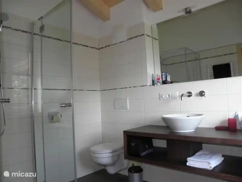 Salle de bain avec douche, WC, double vasque, chauffage au sol et sèche serviette.