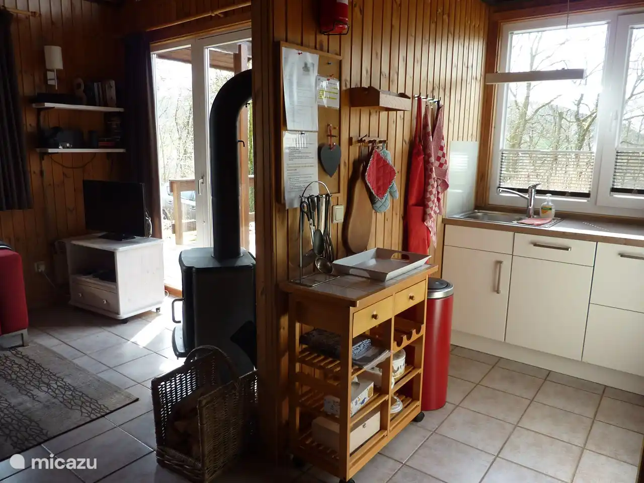 Ein Teil des Wohnzimmers und der Küche mit Zugang zur Terrasse. Die Küche ist mit einem Kombi-Backofen/Mikrowelle und einem Geschirrspüler ausgestattet.