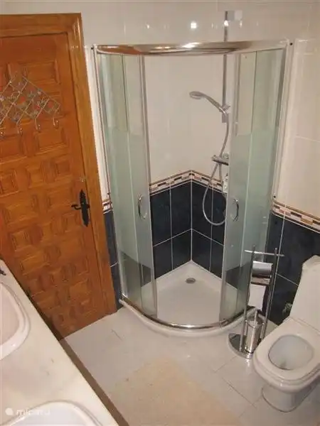 The blue bathroom with shower, bath, 2 sinks and toilet