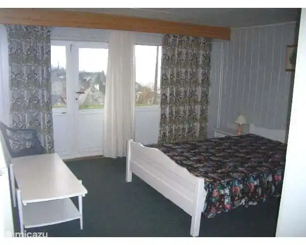 Un dormitorio con una cama doble. La habitación tiene puertas que dan a la terraza y se encuentra en la planta baja.