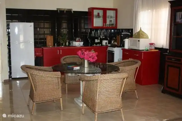cocina con mesa de comedor y 6 sillas de mimbre que forman un todo con la sala de estar