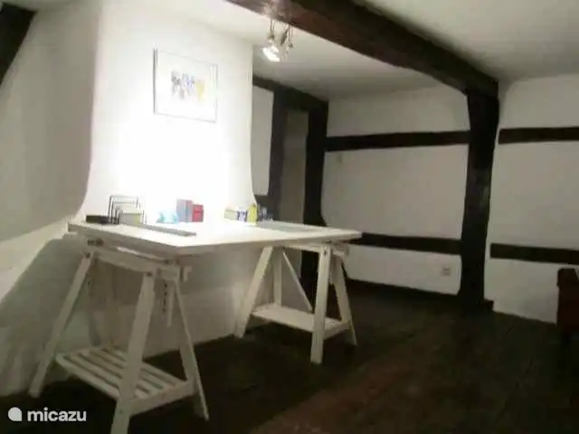 Sala de estar en el dormitorio. Entramado de madera atmosférico con piso de madera antigua y sillón.