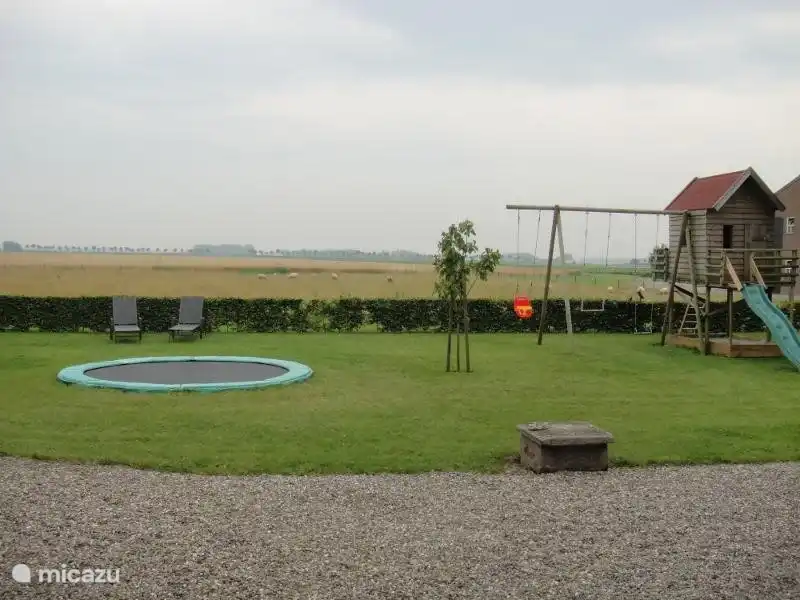 Trampoline, balançoire, maisonnette avec toboggan. Le jardin (ludique) est clôturé.