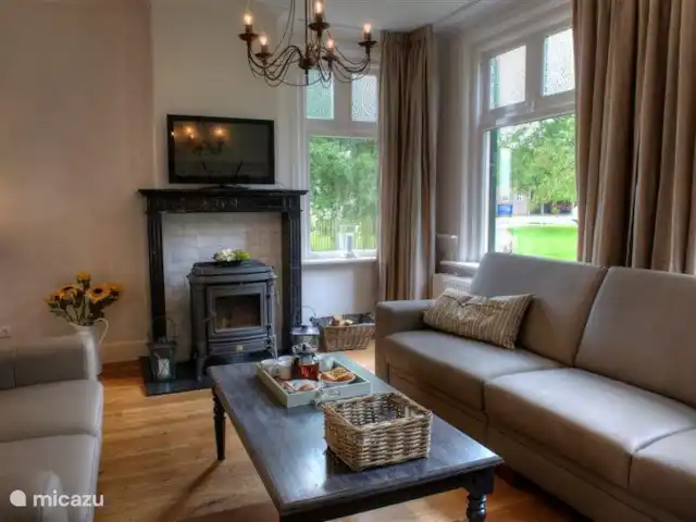 Hof Statendijk | Pays-Bas, Zélande, IJzendijke - ferme une autre vue du coin salon dans le salon. Foyer en marbre avec poêle à bois et un téléviseur au-dessus (télé interactive via internet)