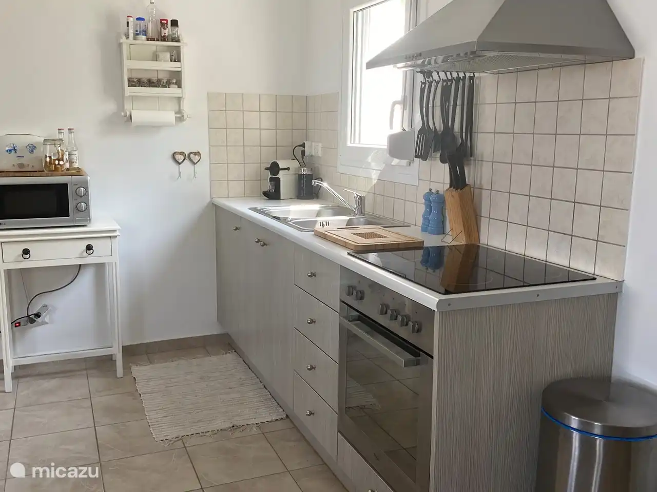 Küche ausgestattet mit Doppelspüle, Umluftbackofen, Herd, Dunstabzugshaube, Nespresso-Kaffeemaschine mit Milchaufschäumer und Mikrowelle.