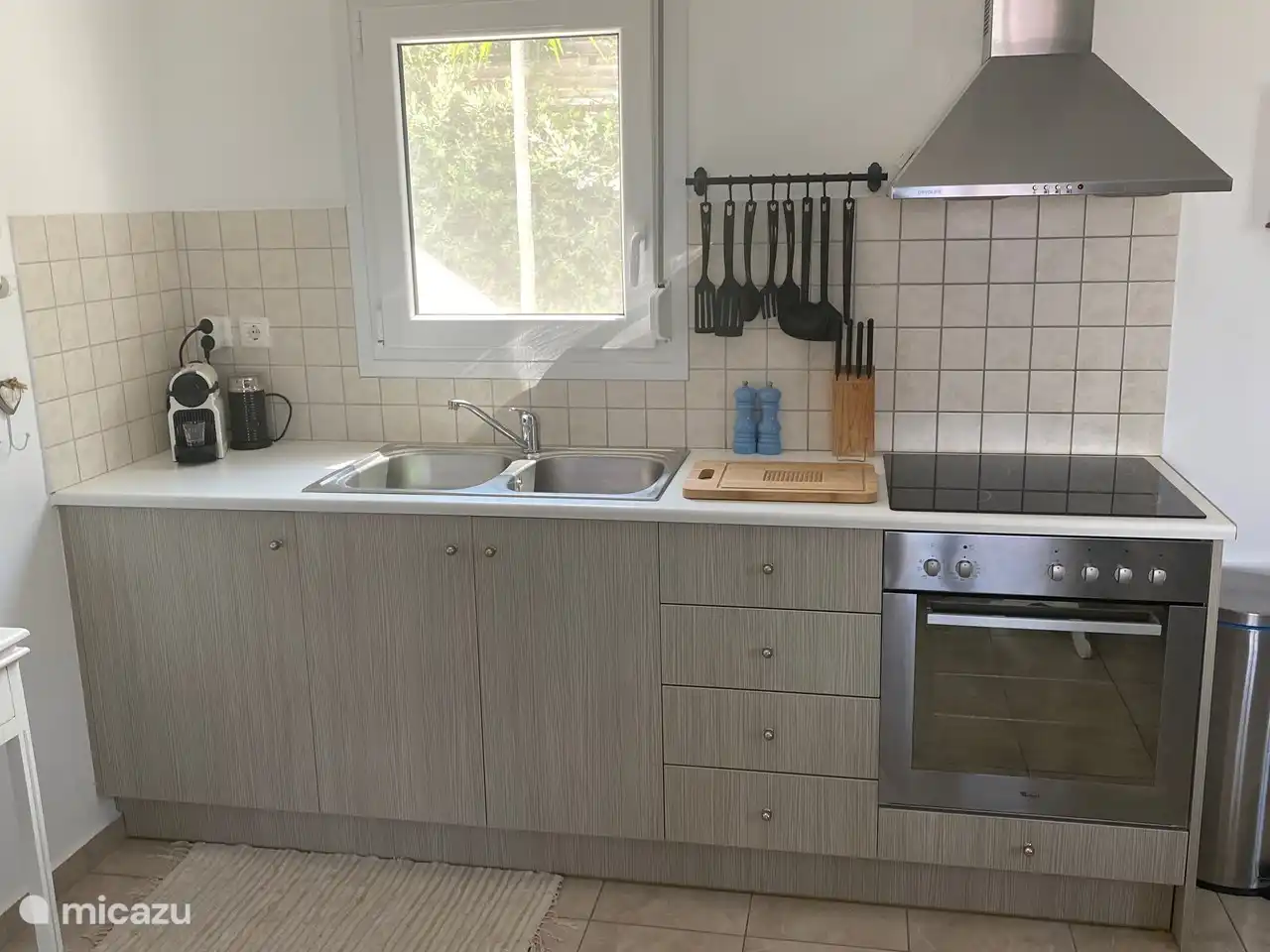 Küche ausgestattet mit Doppelspüle, Umluftbackofen, Herd, Dunstabzugshaube, Nespresso-Kaffeemaschine mit Milchaufschäumer und Mikrowelle.