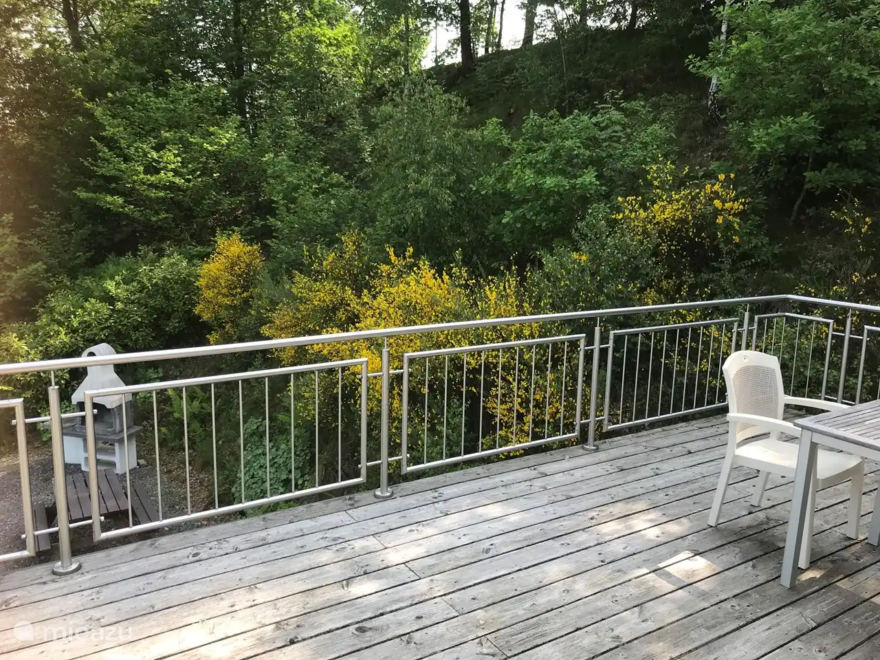 Groot dakterras boven carport met verschillende zitjes en ligbed.