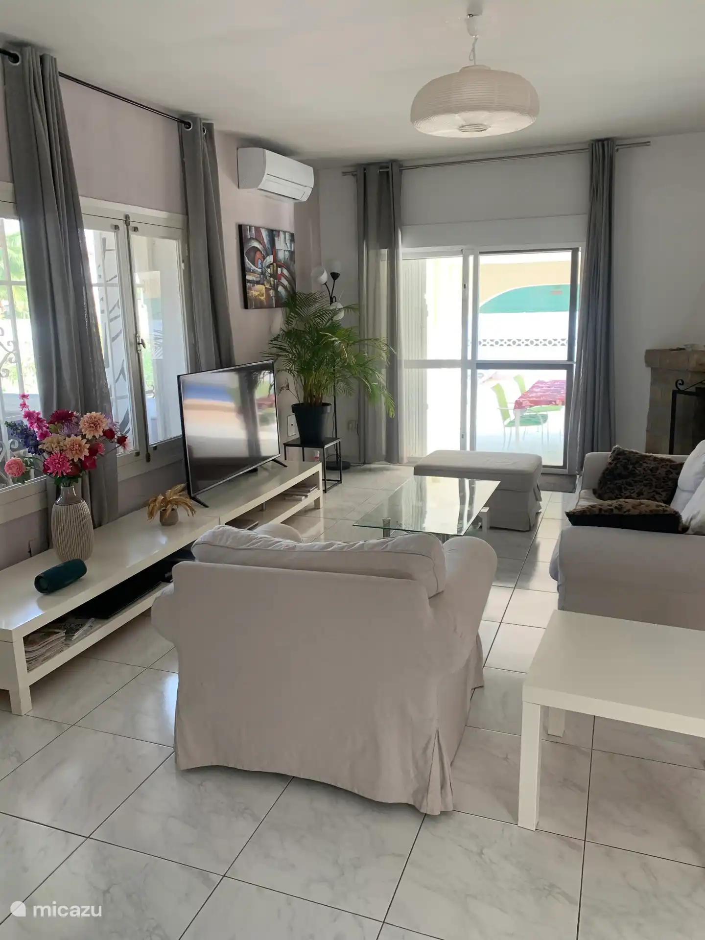 De huiskamer met schuifpui naar overdekt terras en zwembad