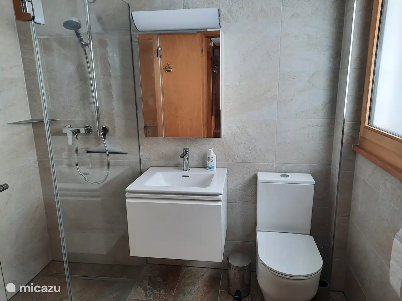 Modern bathroom with spacious walk-in shower, sink and toilet.