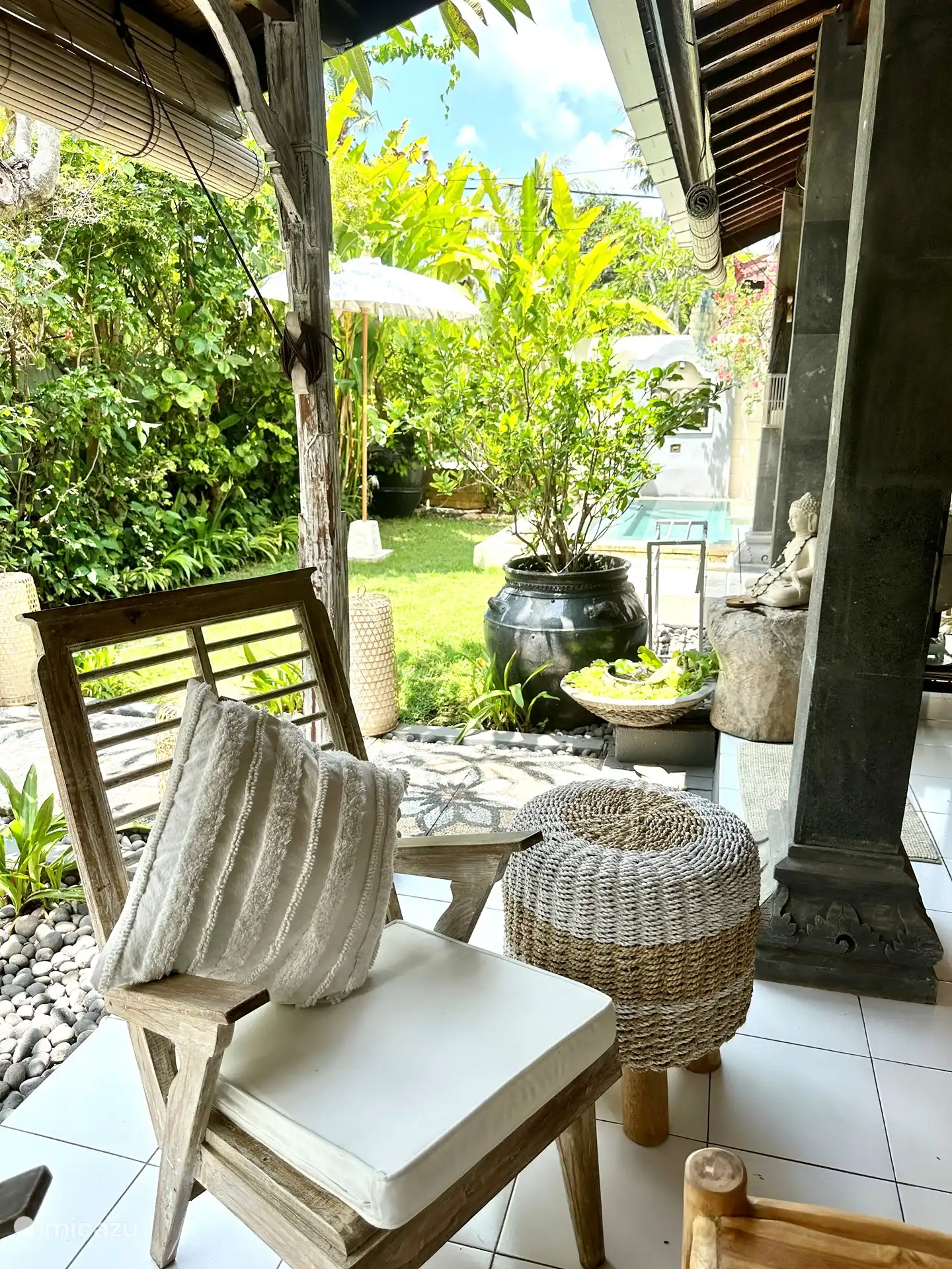 Die Sitzecke gegenüber dem Loungesofa. Hier haben Sie einen Blick auf den Teich und die schöne Bambuspergola mit wunderschönen lila hängenden Blumen, die an Orchideen erinnern. 