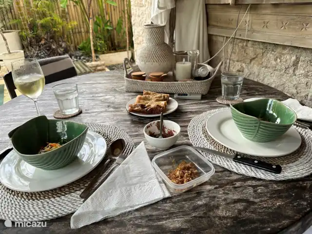 Villa Rumah Pantai No.14 huren in Indonesië, Bali, Jasri - villa Een heerlijke rijsttafel op de tafel onder de veranda van de bungalow, allemaal vers bereid met eigen boemboes door Komang. En in een prachtig servies van bananenbladeren in porselein nieuw in 2024.