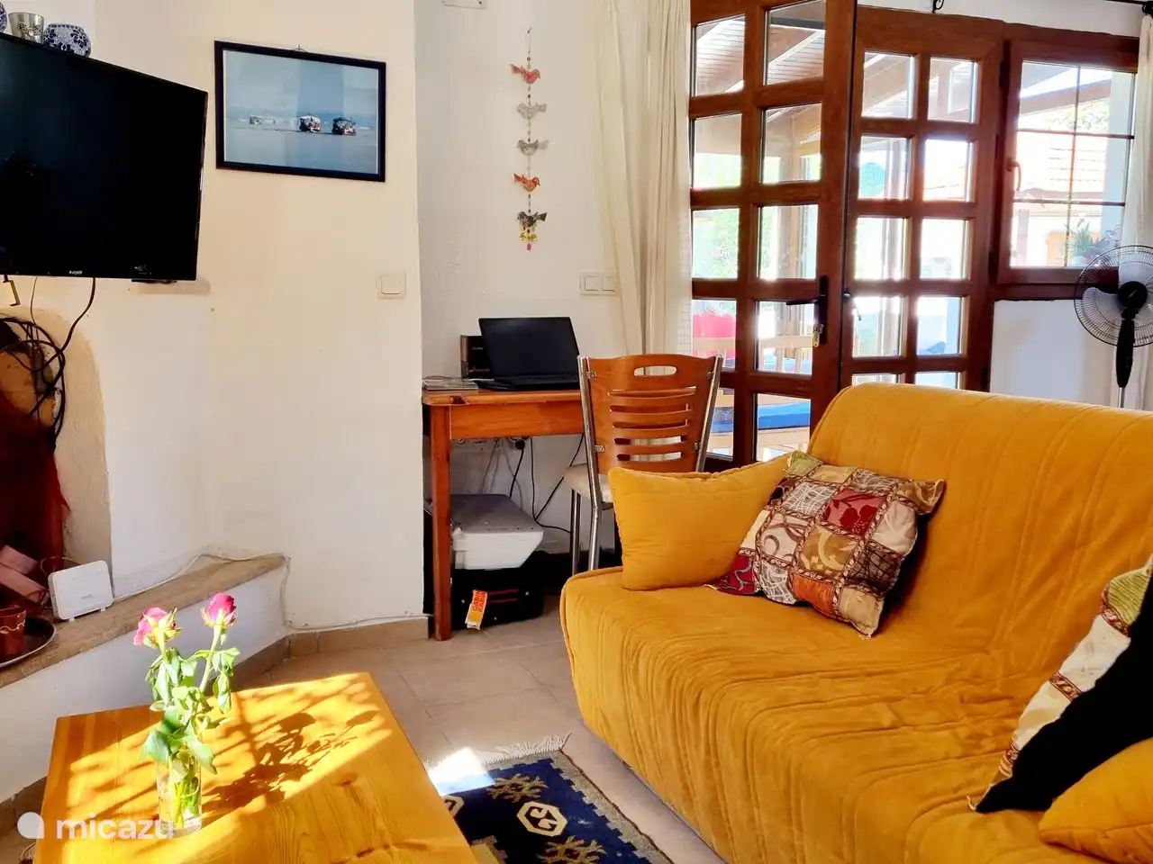 Das Wohnzimmer mit TV und einem Arbeitsplatz