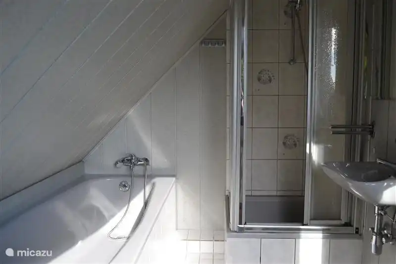 Im Obergeschoss Bad mit Badewanne und Dusche und Waschbecken.