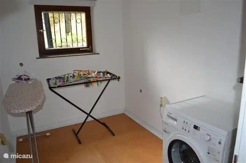 Waschküche mit Waschmaschine und Wäschetrockner und Bügeleisen.