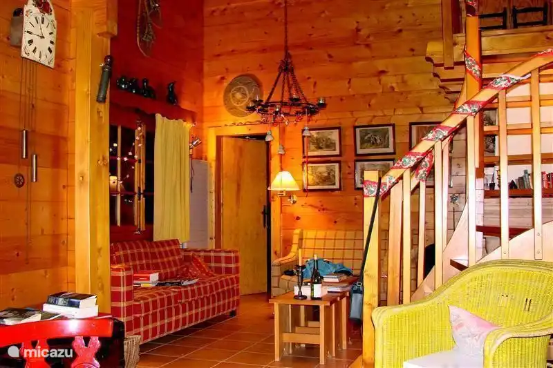 das Wohnzimmer mit Treppe zum Dachboden und Tür zum Schlafzimmer 1 und großem Fenster auf den Balkon