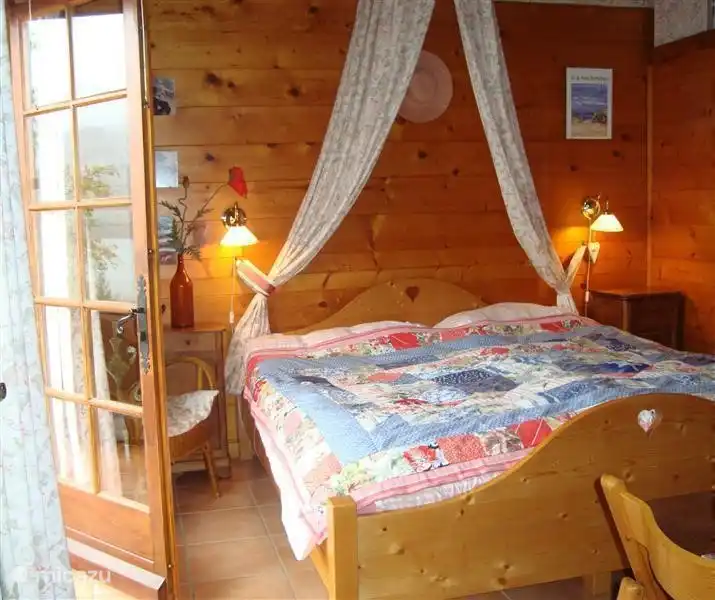 das Hauptschlafzimmer mit Terrassentüren zum Balkon und Blick auf den See