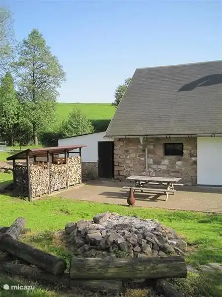 terraza/leñero y plaza de parking al lado de la casa.