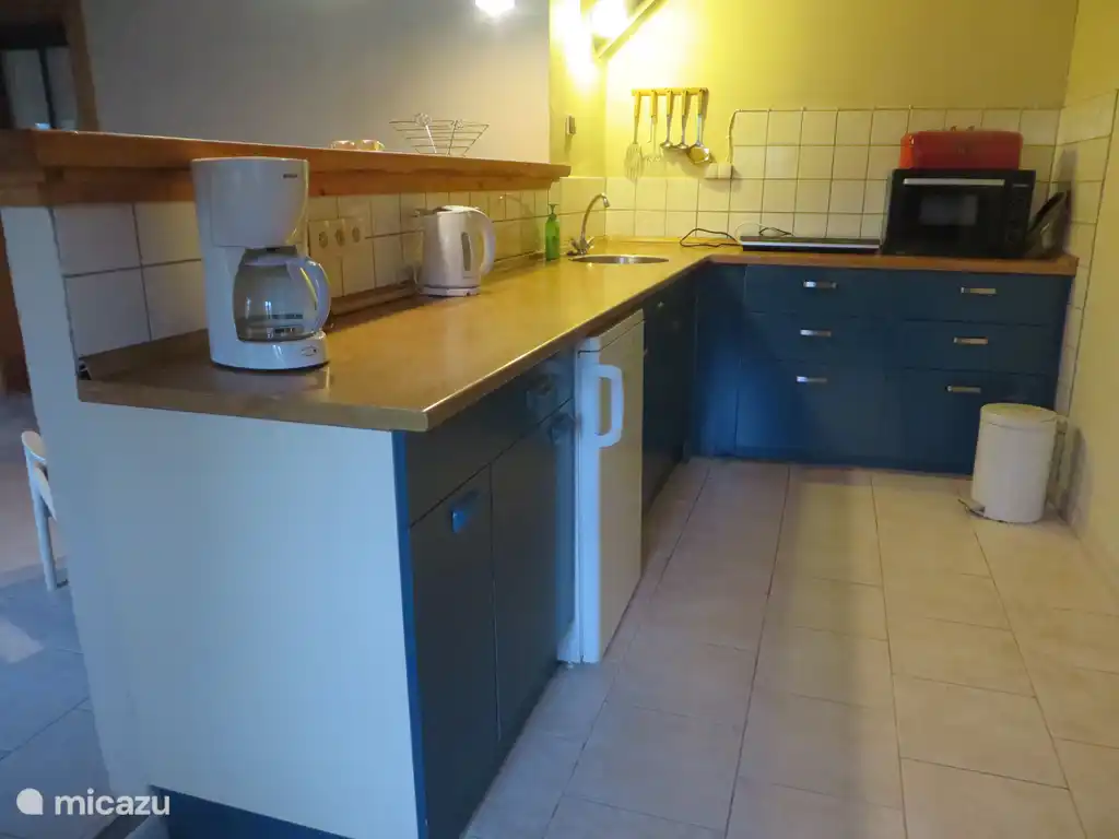 Cocina abierta con cafetera, tetera, horno y placa de inducción de 2 fuegos