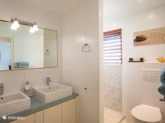 Villa frente al mar en el resort Boca Gentil en Curazao, Banda Arriba (este), Jan Thiel - villa El segundo cuarto de baño con dos lavabos e inodoro y ducha. Este baño tiene vista al frente del jardín.
