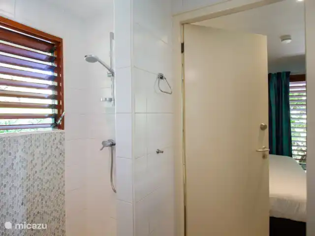 Villa frente al mar en el resort Boca Gentil en Curazao, Banda Arriba (este), Jan Thiel - villa Este es el tercer baño con vista al frente del jardín. esta vez tomada desde un ángulo diferente. Como puedes ver, en este dormitorio hay un televisor y una mesa.