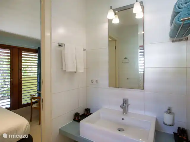 Villa frente al mar en el resort Boca Gentil en Curazao, Banda Arriba (este), Jan Thiel - villa Este es el tercer baño con vista al frente del jardín. esta vez tomada desde un ángulo diferente. Como puedes ver, en este dormitorio hay un televisor y una mesa.